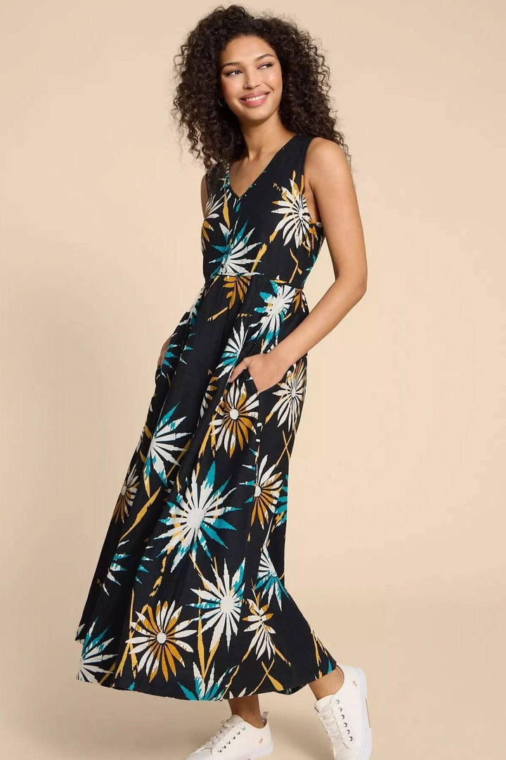 Robe Gigi longue en lin mélangé avec imprimé floral sur fond noir, portée par un mannequin souriant.