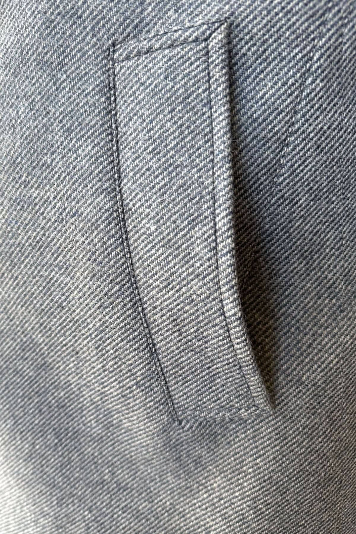 Détail d'une poche d'un manteau caban doublé élégant en tissu gris.