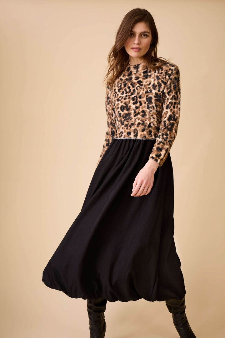 Femme portant un chandail duveteux à motif animal avec une jupe fluide noire, créant un look élégant et audacieux.
