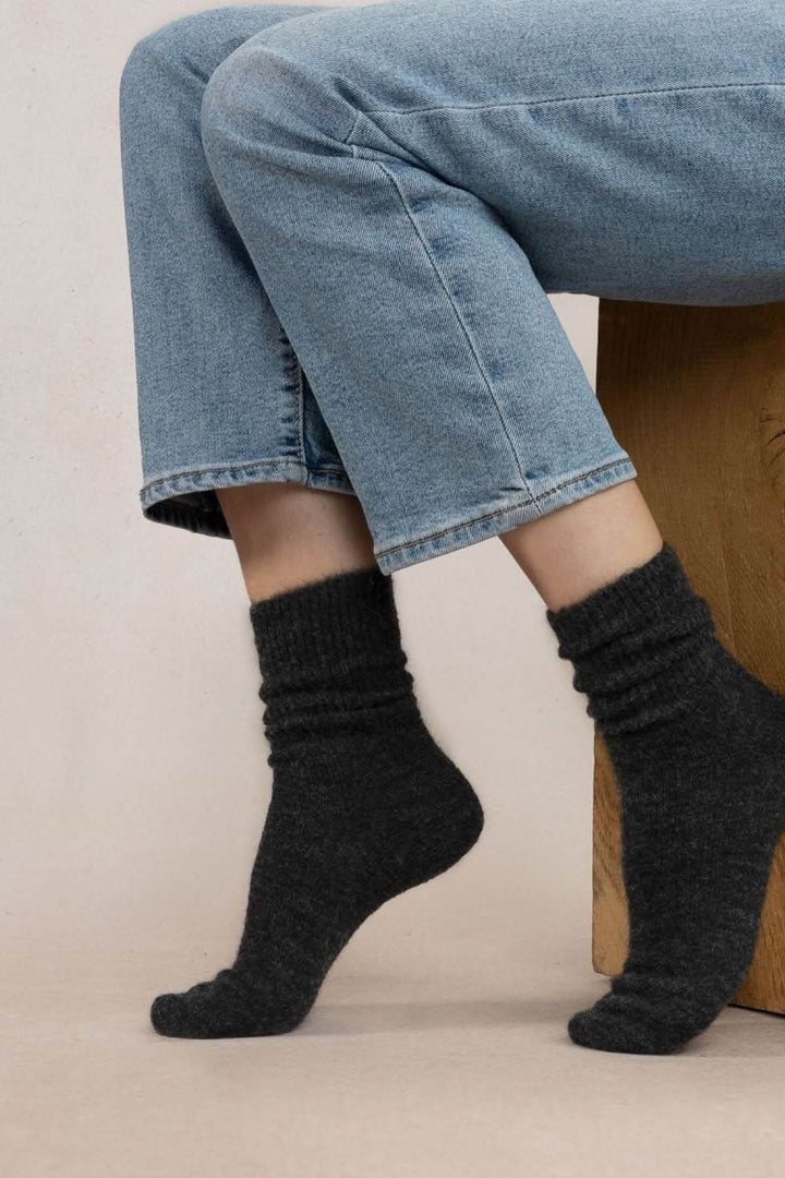 Chaussettes en laine alpaga gris foncé portées, offrant chaleur et confort, associées à un jean.