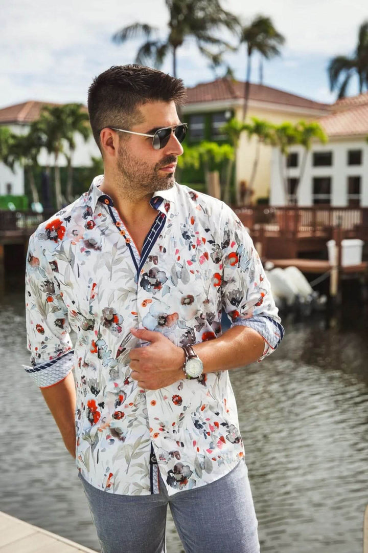 Homme portant une chemise à imprimé floral près d'un canal, avec un col structuré et des détails contrastés.