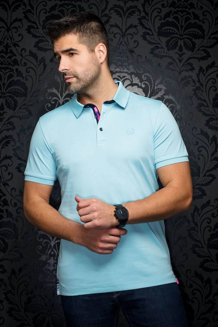 Homme portant un polo bleu uni avec détails contrastants, montrant élégance et confort.