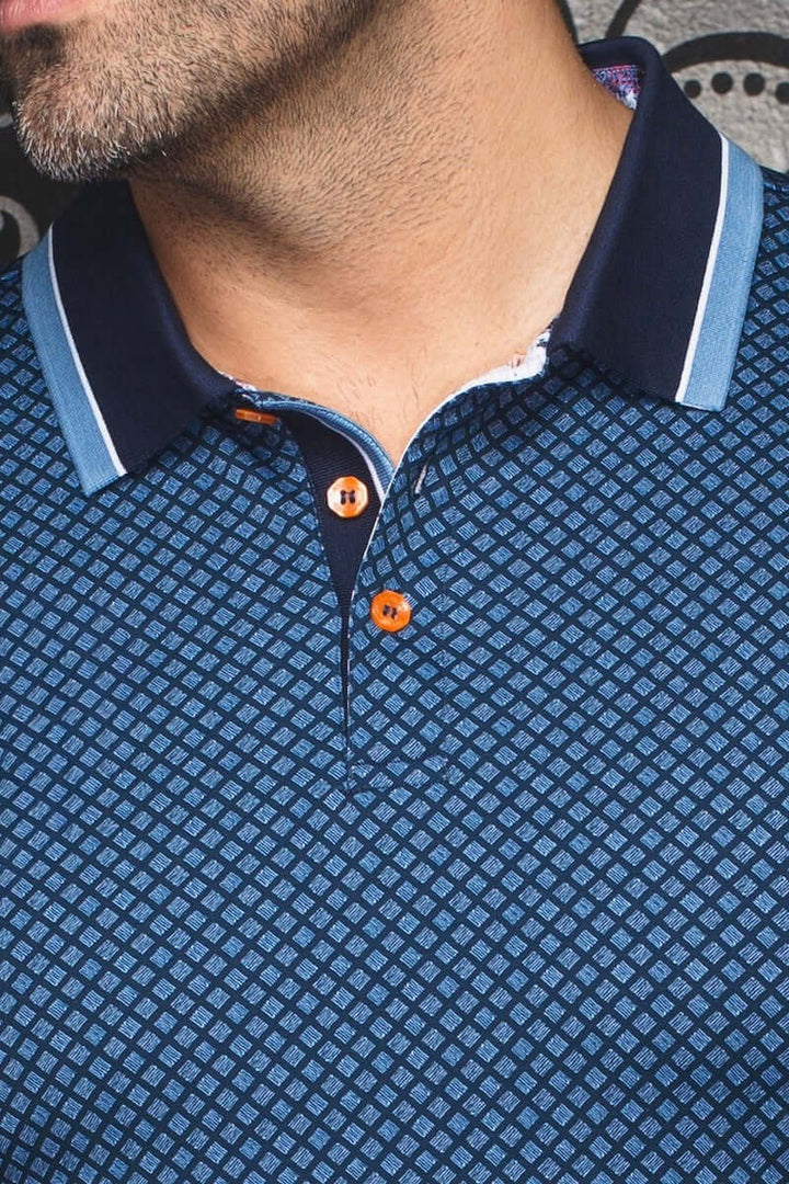 Polo géométrique contemporain avec col marine et liseré bleu clair, détails de boutons contrastants.