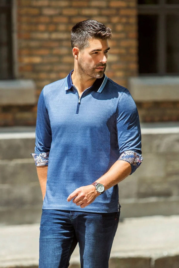 Homme portant un polo décontracté bleu avec détails floraux et col contrastant, parfait pour un look élégant.