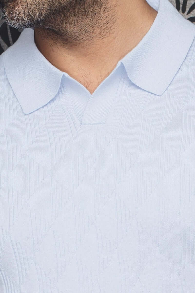 Polo Lowick en maille fine, col ouvert, couleur bleu clair, avec texture discrète et manches courtes.