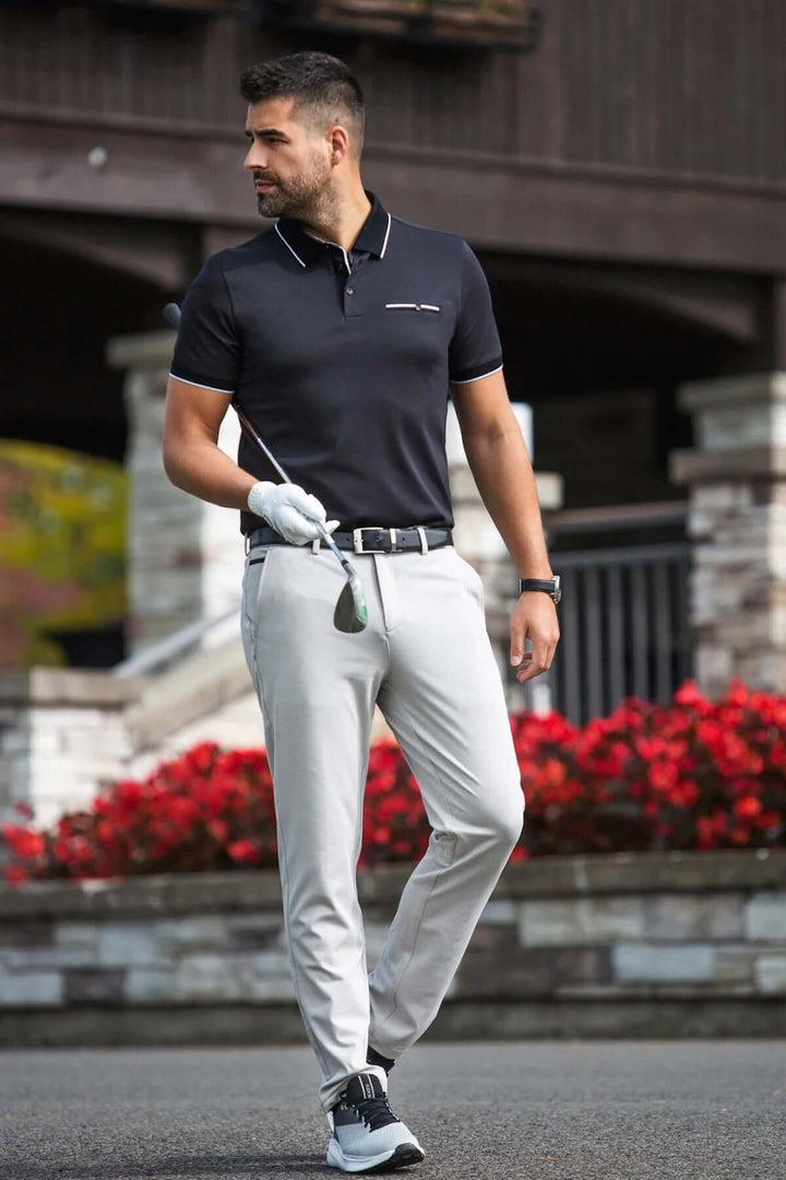Polo élégant à manches courtes, détails contrastants, porté par un homme sur un terrain de golf.