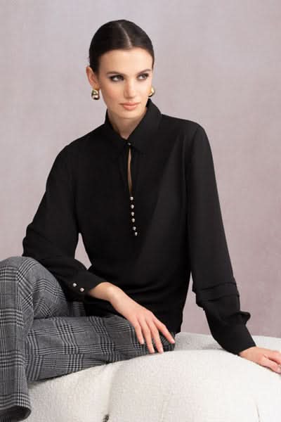 Blouse classique noire à encolure V et boutons décoratifs, portée avec un pantalon à carreaux.