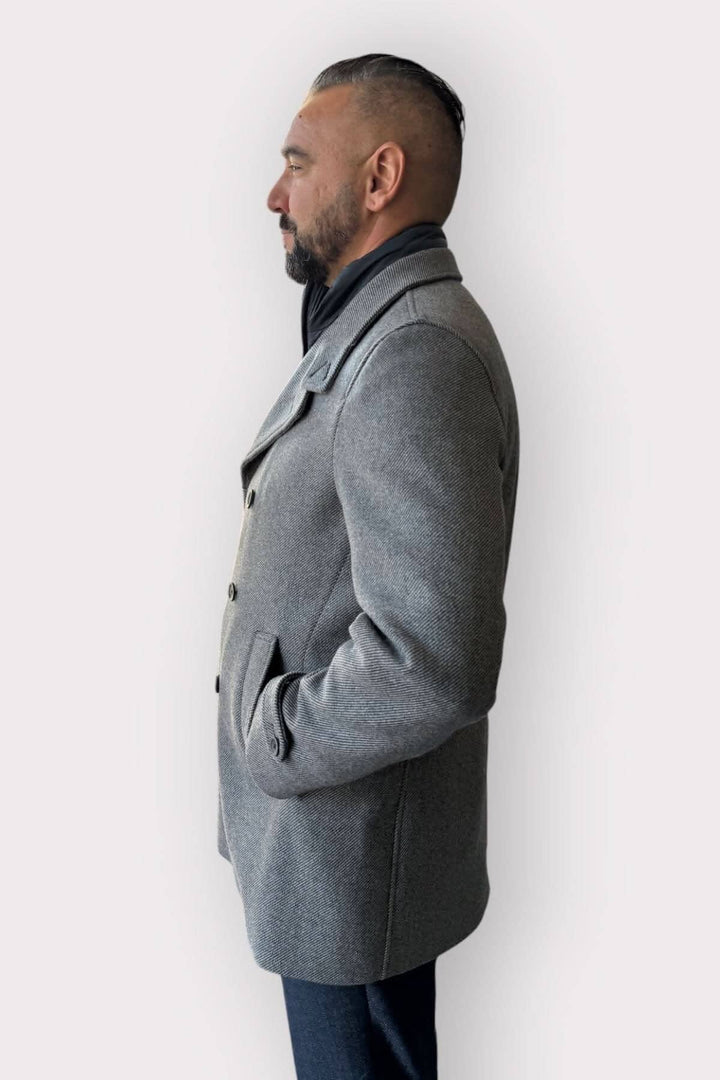 Homme portant un manteau caban doublé gris, avec col montant et boutonnage sophistiqué.