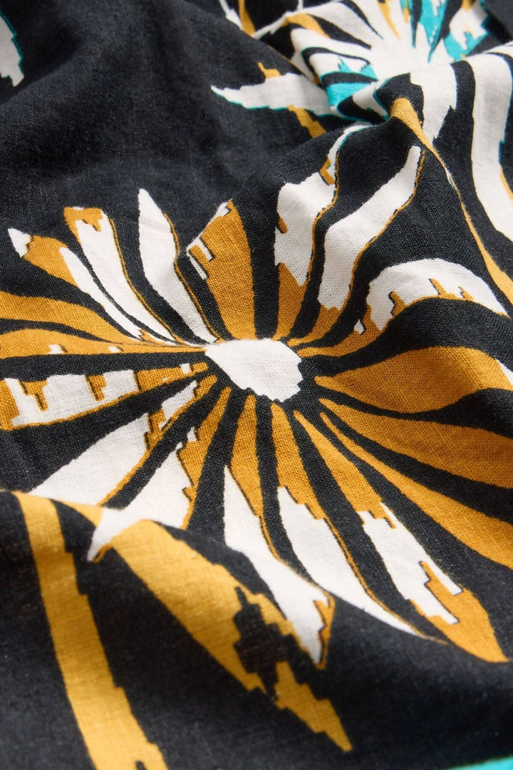 Détails du tissu en lin mélangé de la robe Gigi avec un motif floral en noir, blanc et doré.