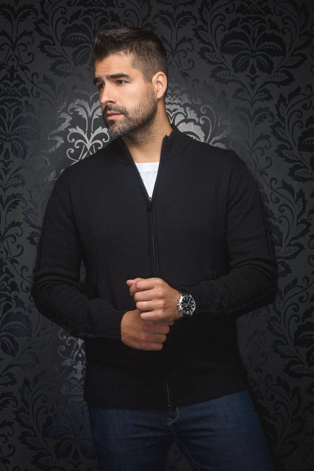 Homme portant un chandail à zip en laine mérinos extra fine, style classique, couleur noire sur fond texturé.
