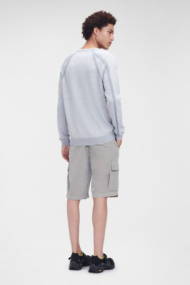 Homme de dos portant un pull gris à col ras du cou et un short cargo beige, dans un style décontracté.