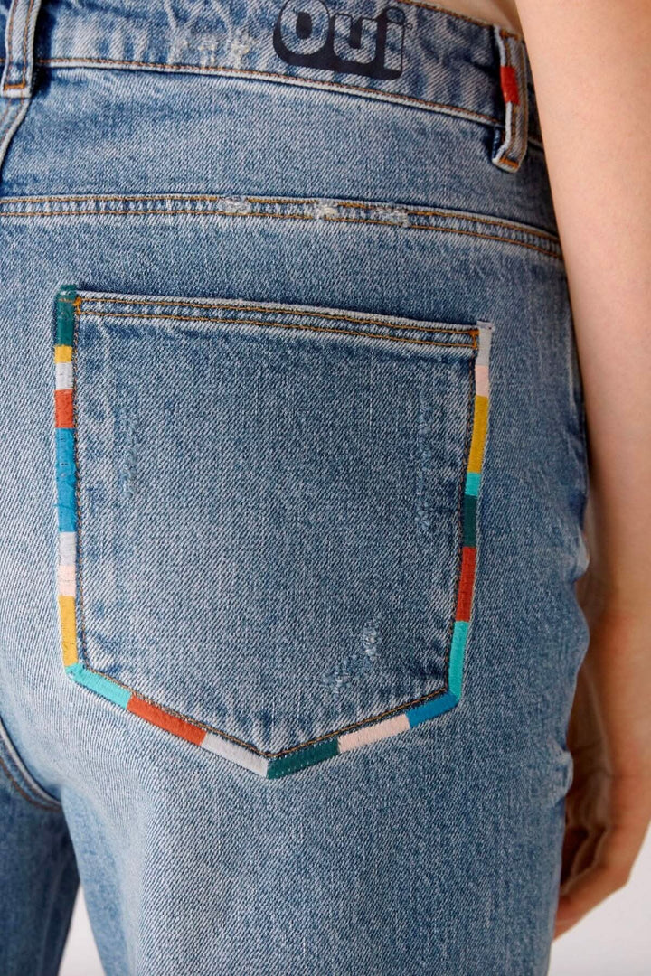 Jean pâle à jambe droite avec détails de coutures colorés sur la poche arrière.
