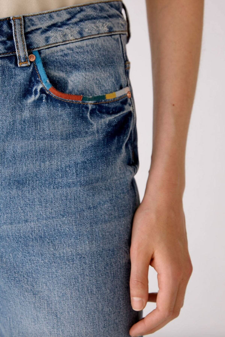 Jean pâle à jambe droite avec détails colorés sur la poche, 100% coton, style original et tendance.