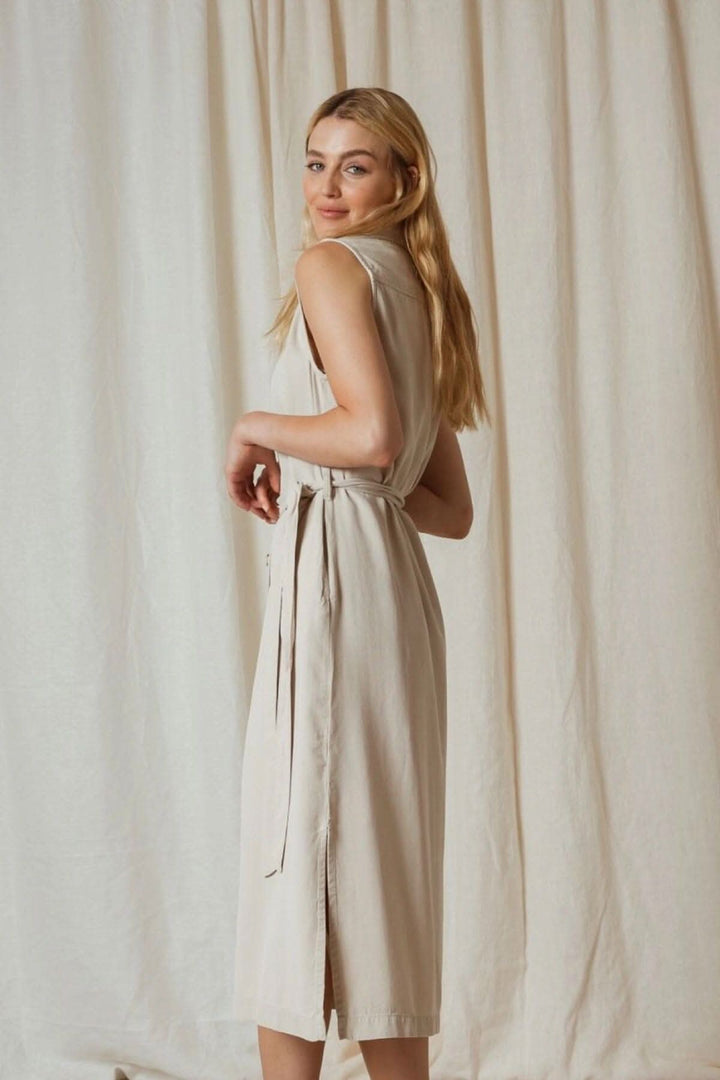 Robe en piqué de lyocell beige portée par une modèle, avec ceinture et ouverture dans le dos.