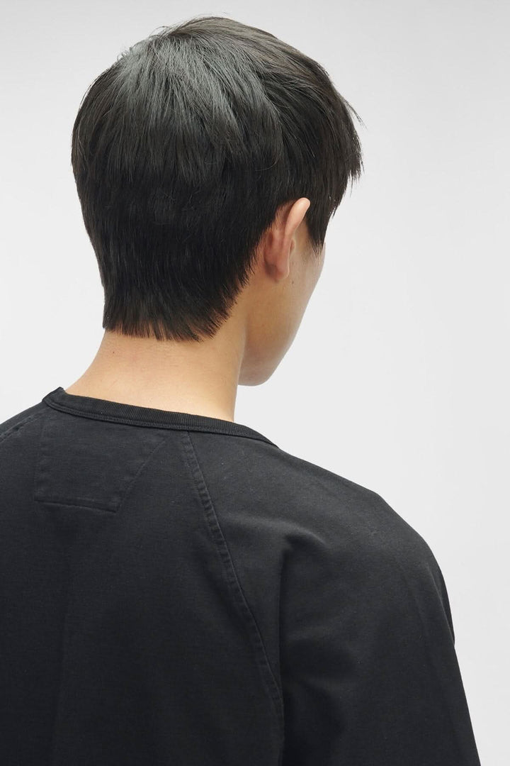 Homme portant un t-shirt en jersey épais noir, vue de dos, avec coupe moderne et col ras du cou.