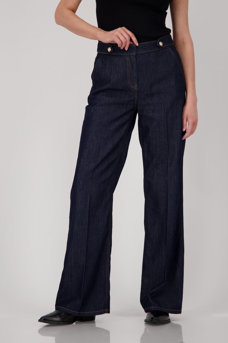 Jean taille haute en denim brut, coupe droite et ample, ceinture à passants et boutons métalliques sur le devant.