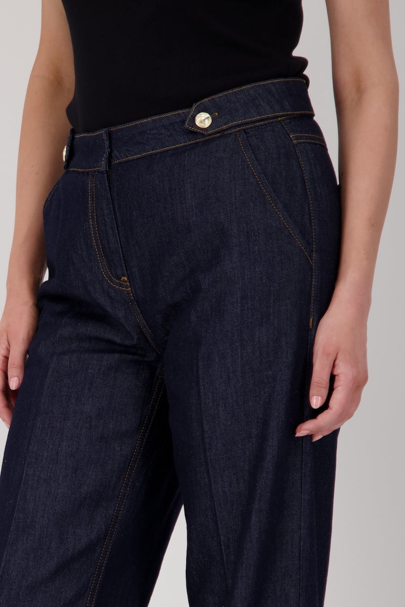 Jean taille haute en denim brut, coupe droite avec ceinture à passants et boutons métalliques.