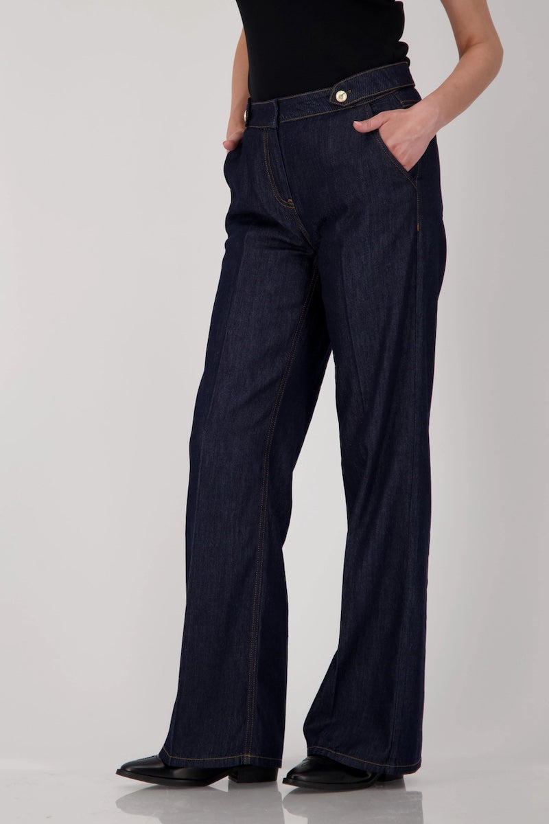 Jean taille haute en denim brut, coupe droite et ample, longueur chevilles, avec ceinture à boutons métalliques.