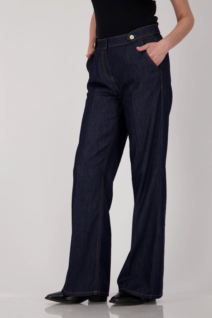 Jean taille haute en denim brut, coupe droite et ample, longueur chevilles, avec ceinture à boutons métalliques.