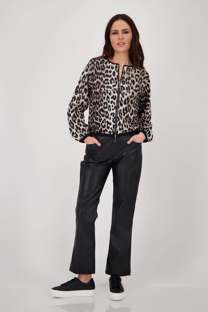 Femme portant une veste léopard élégante avec pantalon noir, style moderne et audacieux, look sophistiqué.