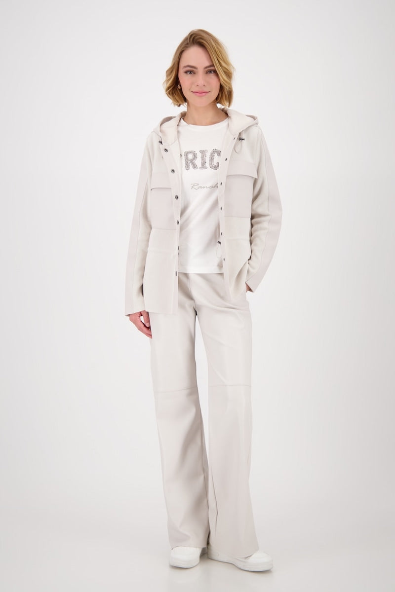 Femme portant une veste à capuchon beige et un pantalon assorti, style décontracté avec un t-shirt graphique.