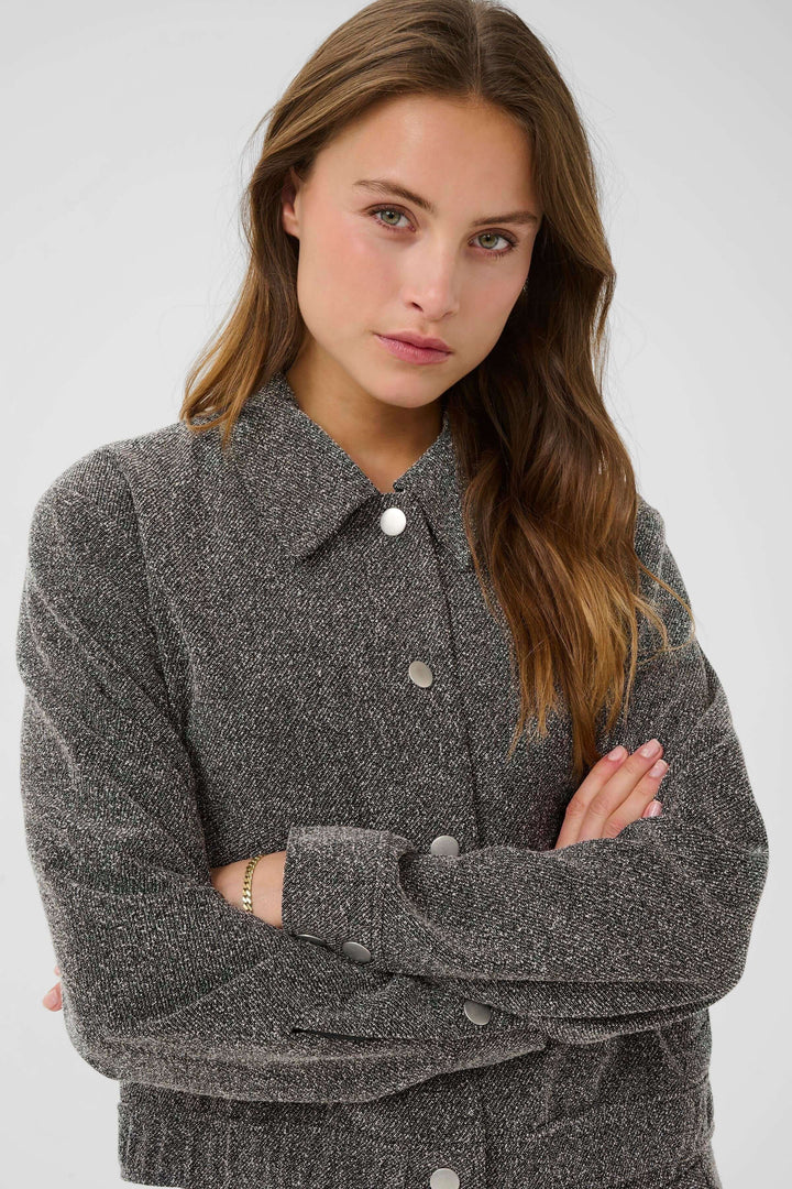 Modèle portant un Manteau Alba court à poches à rabat et boutons contrastants, dans un style moderne et chic, idéal pour diverses tenues.