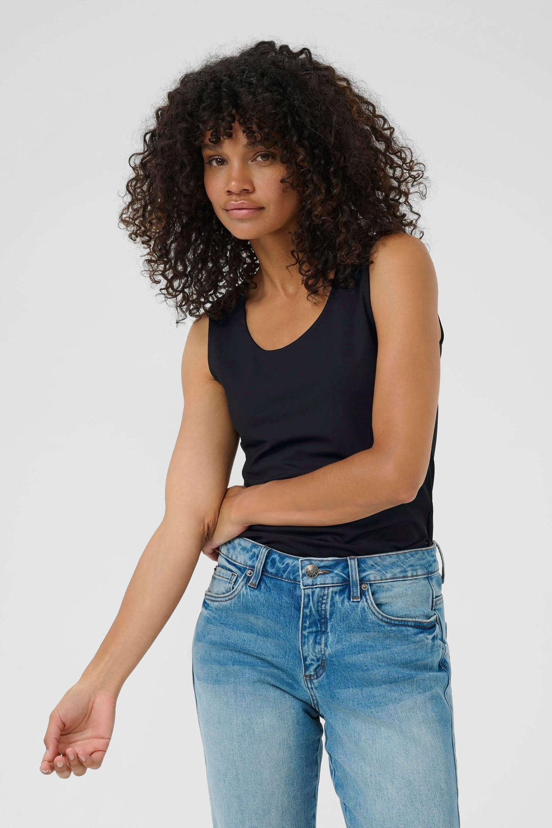 Person wearing a black tank top with blue jeans, standing in a neutral pose.