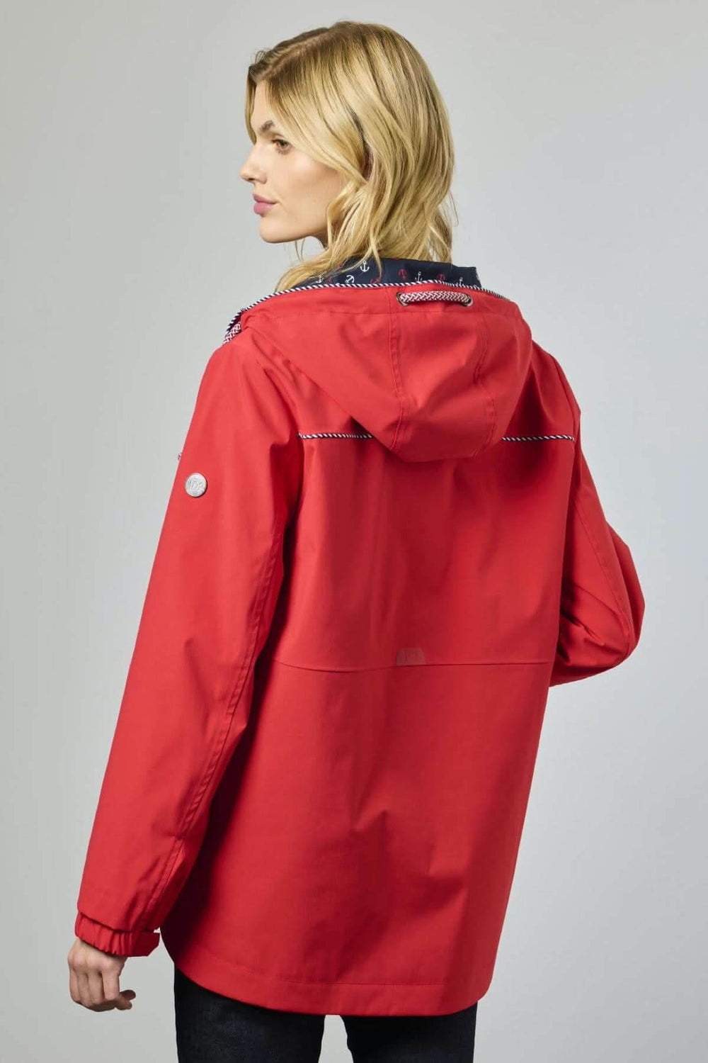 Femme portant une veste rouge imperméable avec capuche, vue de dos. 2290-88 Décris moi le produit en français.