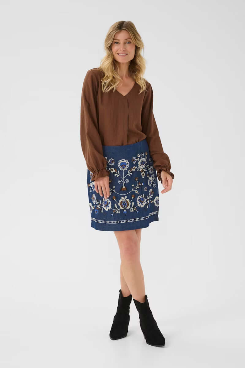 Jupe Gro en denim avec broderies florales, coupe droite au-dessus du genou, style bohème chic parfait pour look décontracté élégant.