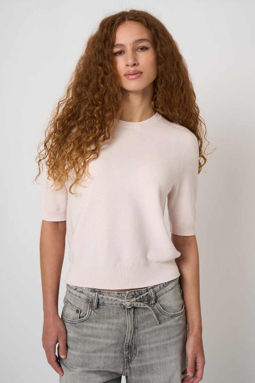 Tricot à manches courtes élégant en maille fine pour femme, porté avec un jean.