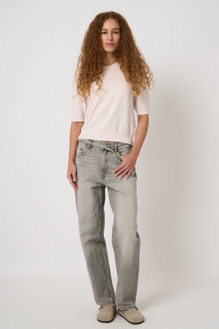 Tricot à manches courtes, élégant et minimaliste, porté avec un jean pour un style décontracté et polyvalent.