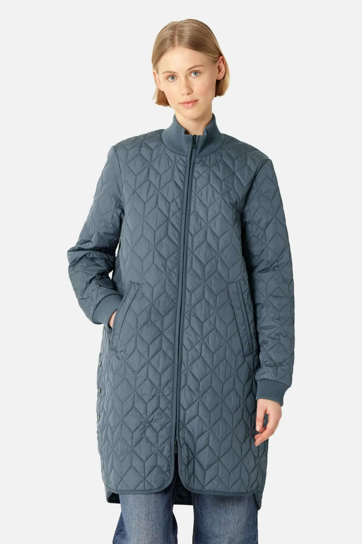 Femme portant un manteau matelassé long à col montant avec motifs géométriques, idéal pour un look urbain élégant par temps frais.