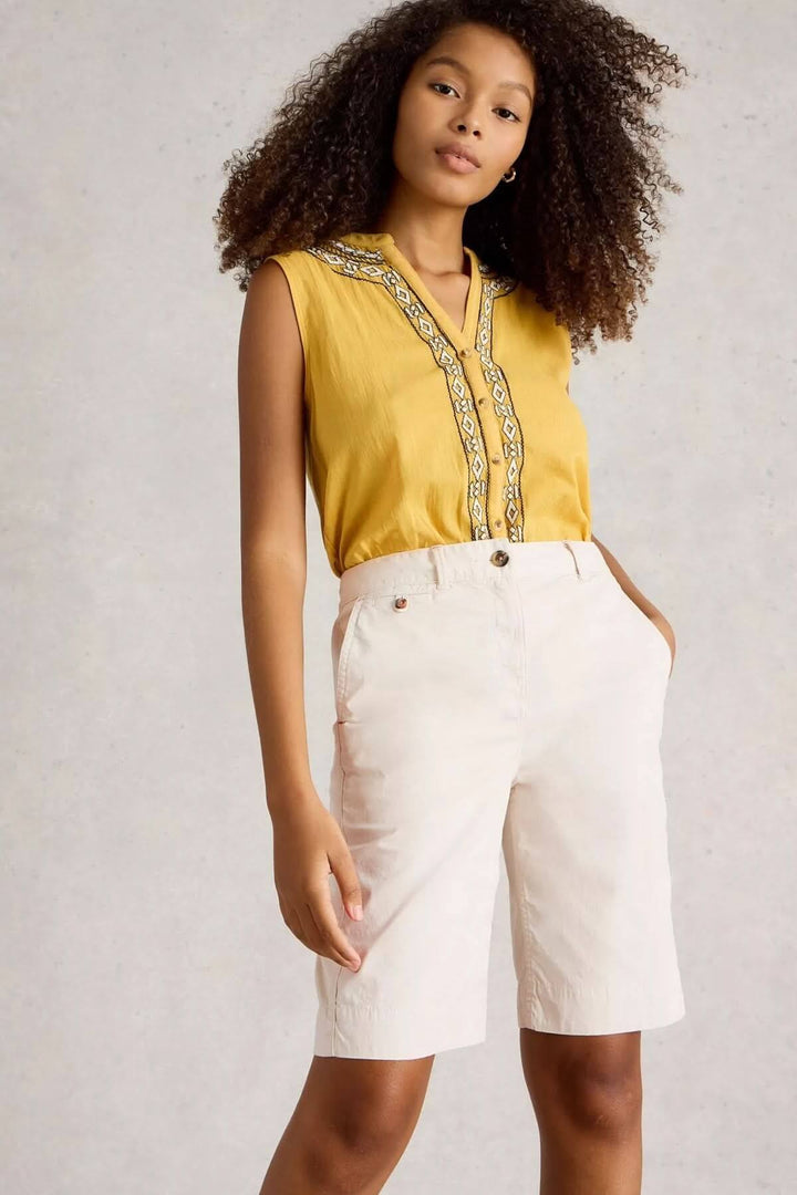 Femme portant un bermuda en coton naturel, coupe au-dessus du genou, associé à un haut jaune élégant.