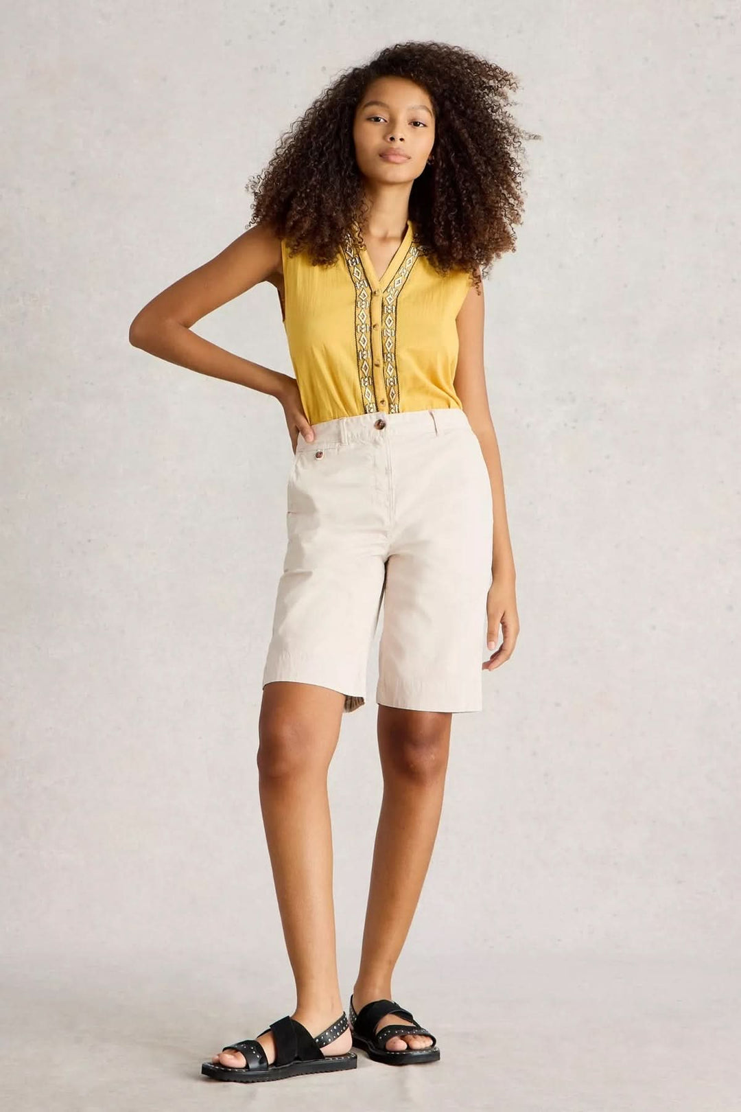 Model wearing Bermuda Hayley cotton shorts paired with a yellow top, showcasing a fresh summer look.