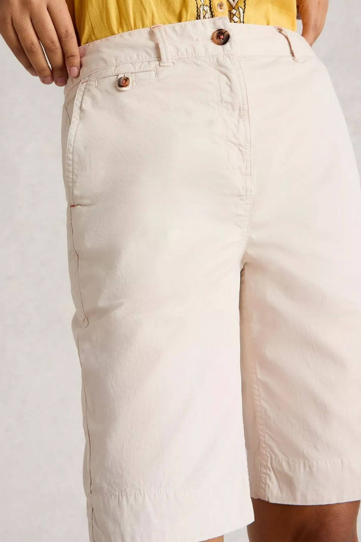 Bermuda shorts in light cotton, showcasing a knee-length fit and button closure, styled with a vibrant summer top.