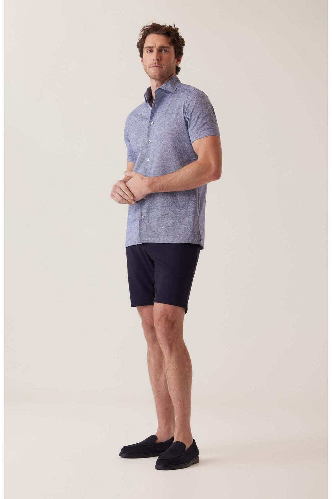 Homme portant un polo bleu et un short noir, prêt pour un look décontracté et stylé.