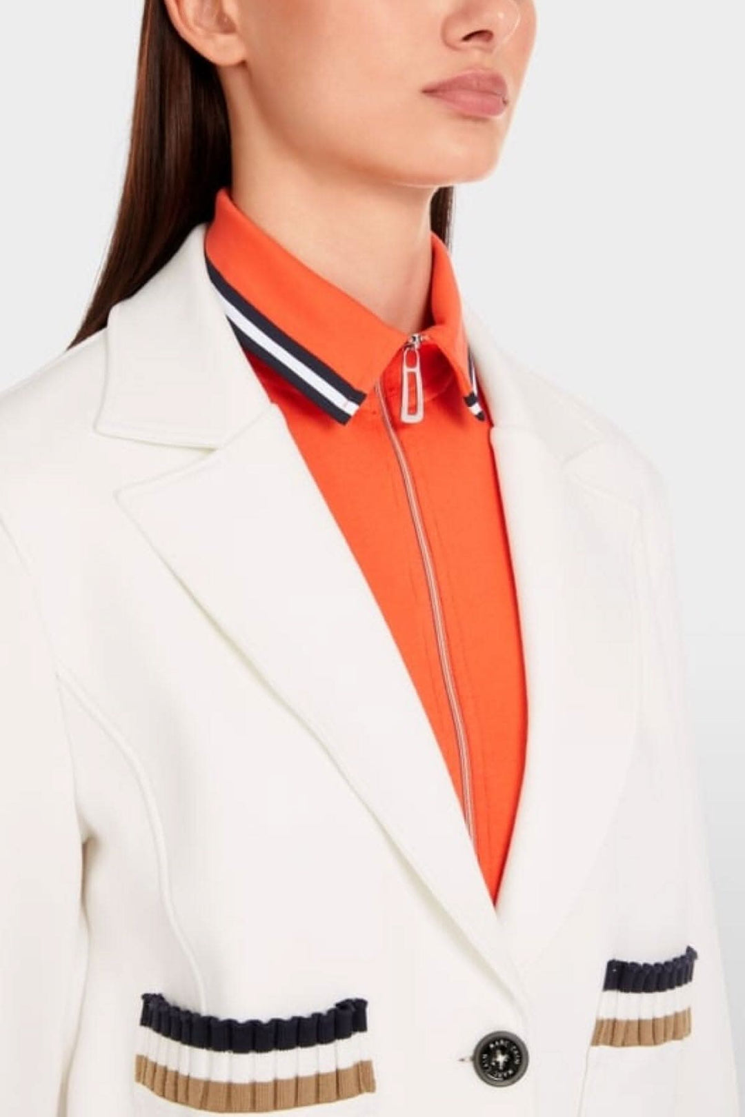 Close-up of a model wearing a white jersey blazer with striped details and an orange zip-up collar shirt.
