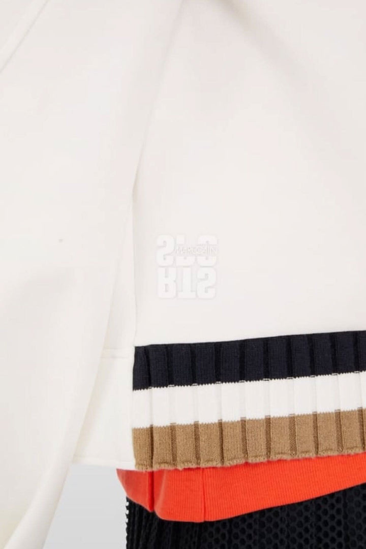 Close-up of a stylish white sweater sleeve with ribbed color-blocked hem and orange detailing.