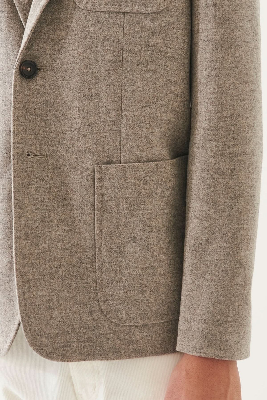 Détail d'un blazer en laine à deux boutons, couleur beige, avec poches plaquées et texturé.
