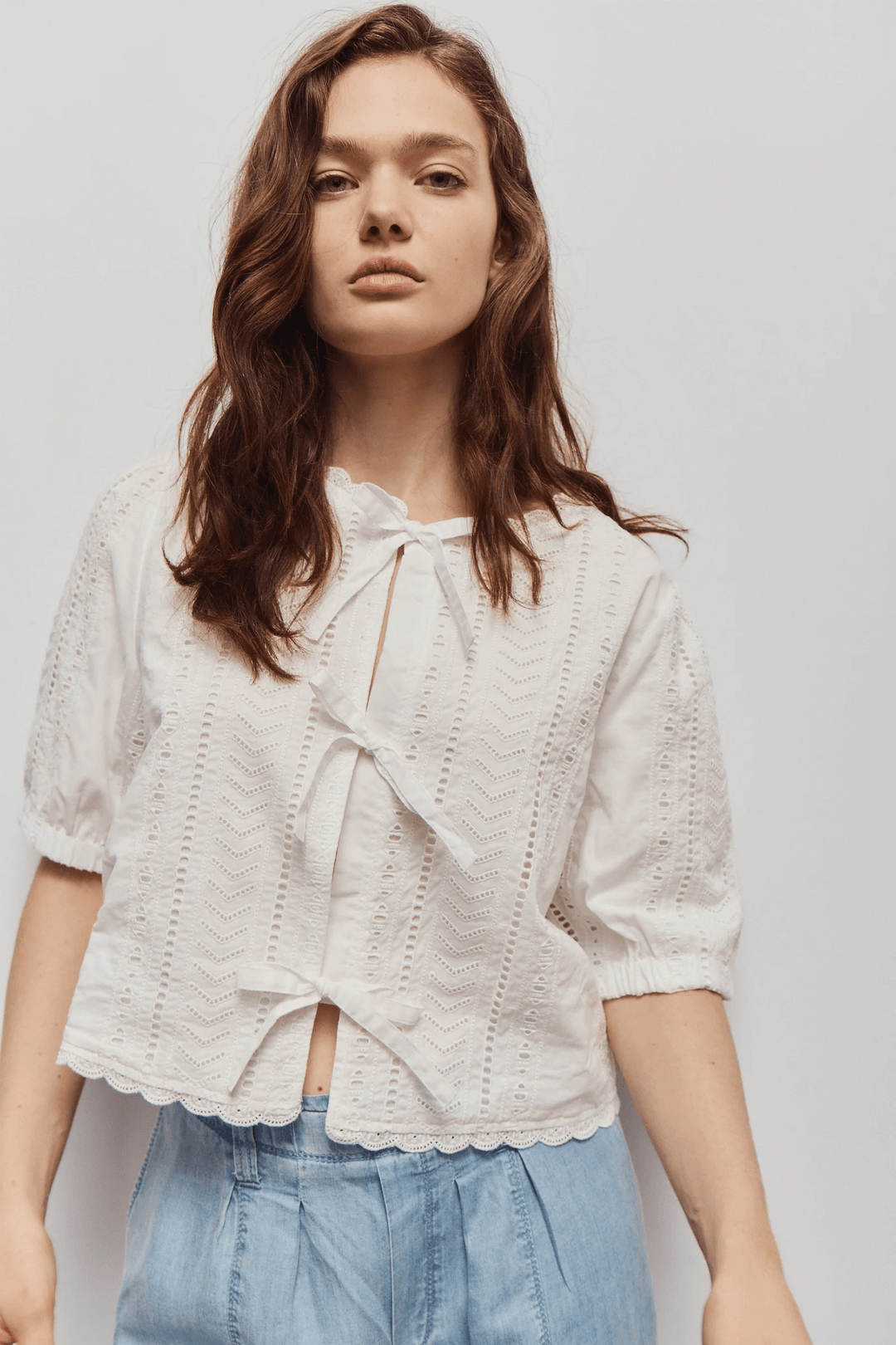 Modèle portant la Blouse Giana brodée à nouer avec broderies ajourées et manches courtes, idéale pour l'été, vue de face.