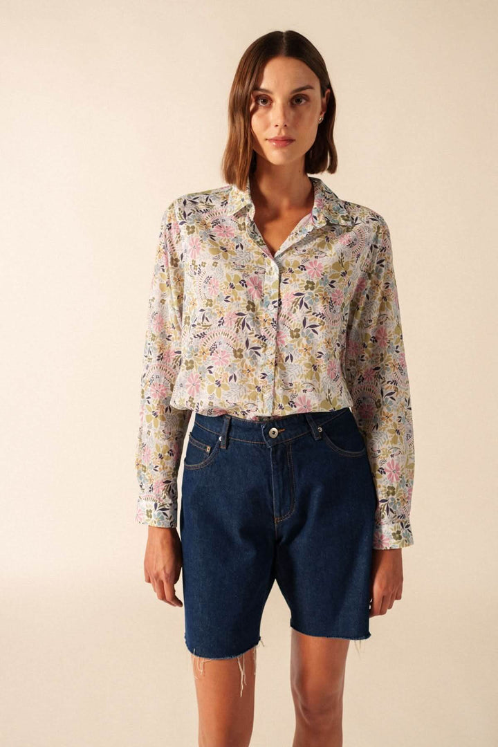 Blouse JEANNE ML à imprimé floral coloré, manches longues, col classique et tissu fluide, portée avec un short en jean bleu.