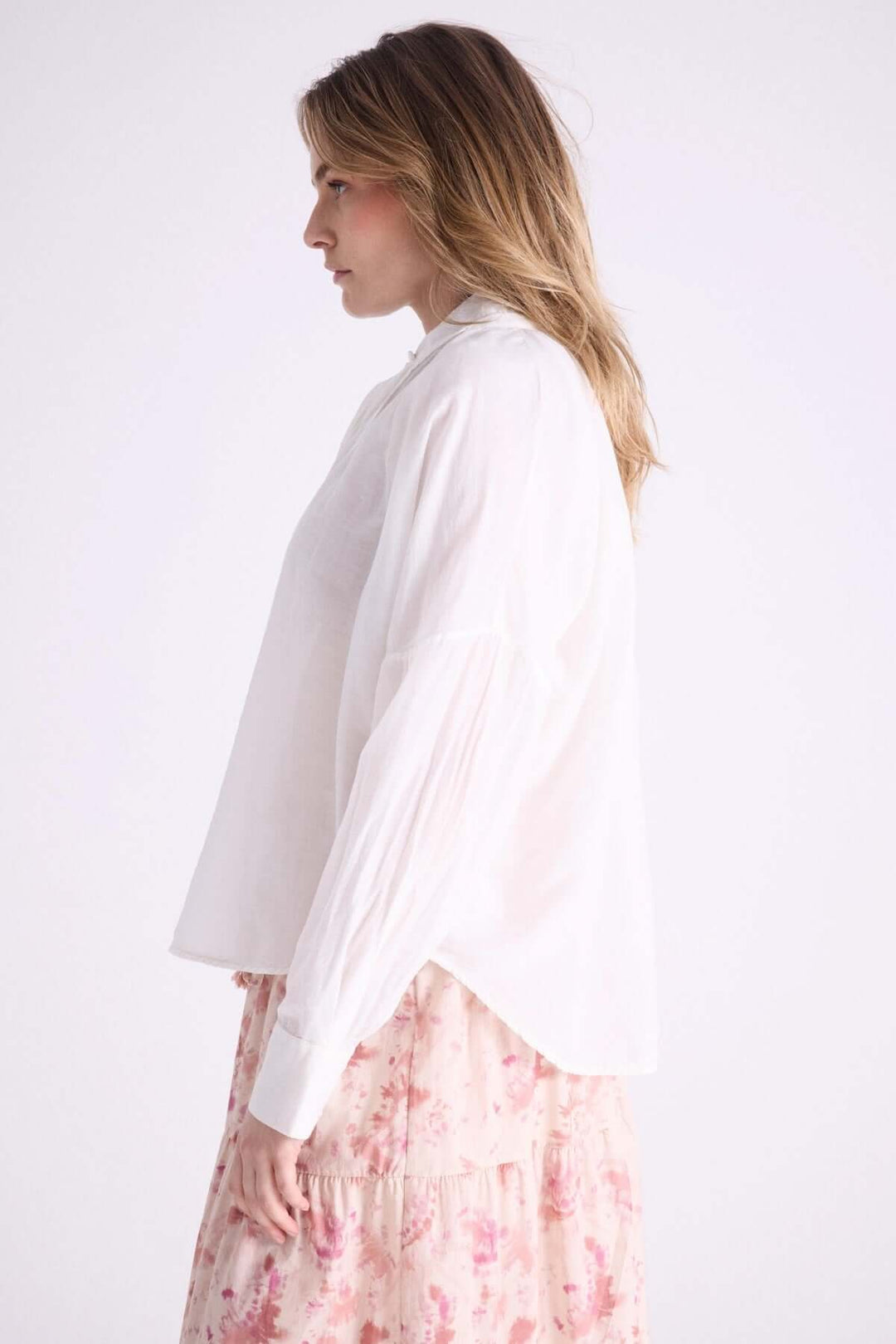 Blouse légère à capuche avec cordons à pompons, parfaite pour les journées estivales, portée avec une jupe fleurie.