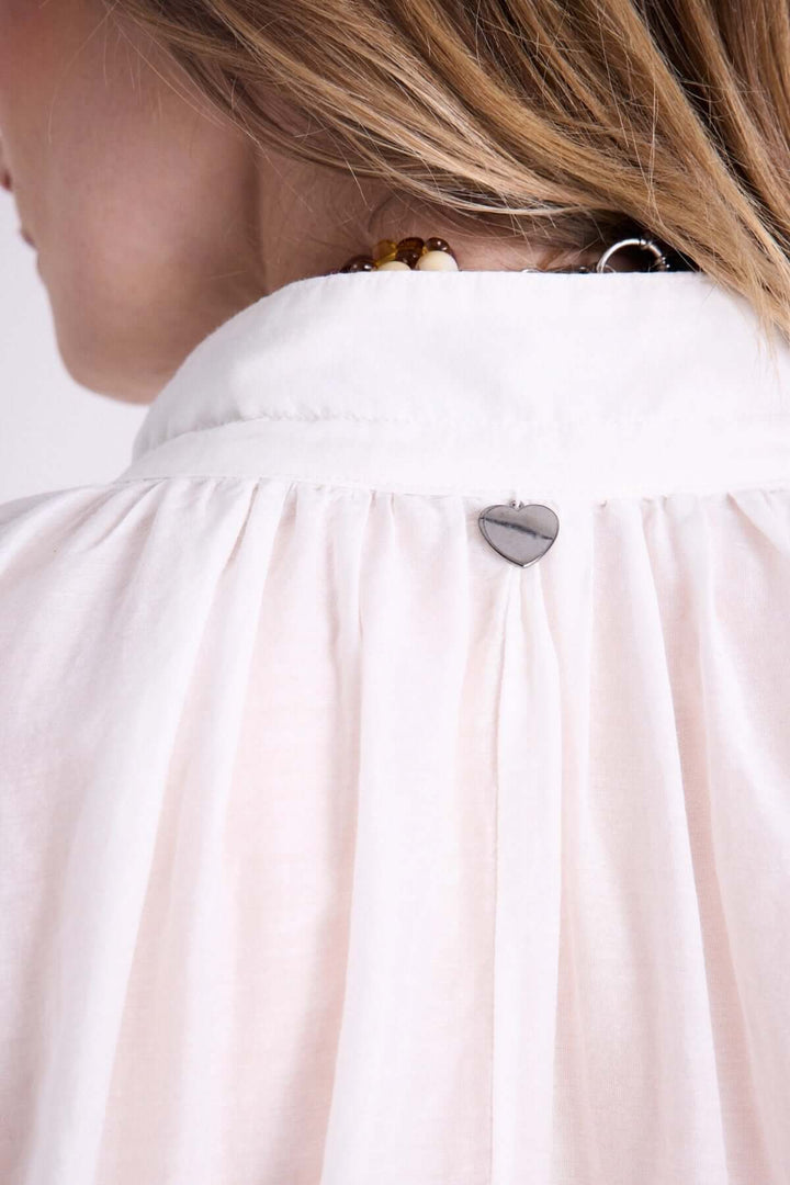 Vue arrière d'une blouse légère à capuche avec détail de cordon et bijou en forme de cœur.