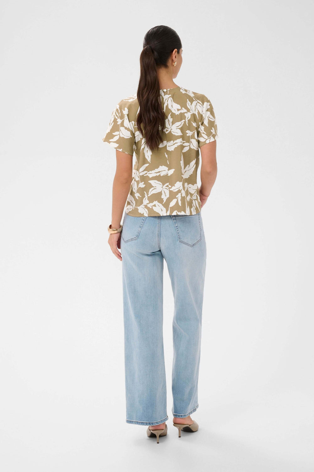 Femme de dos portant la Blouse Marlo fluide à imprimé feuillage avec manches courtes et encolure ronde, style léger et élégant.