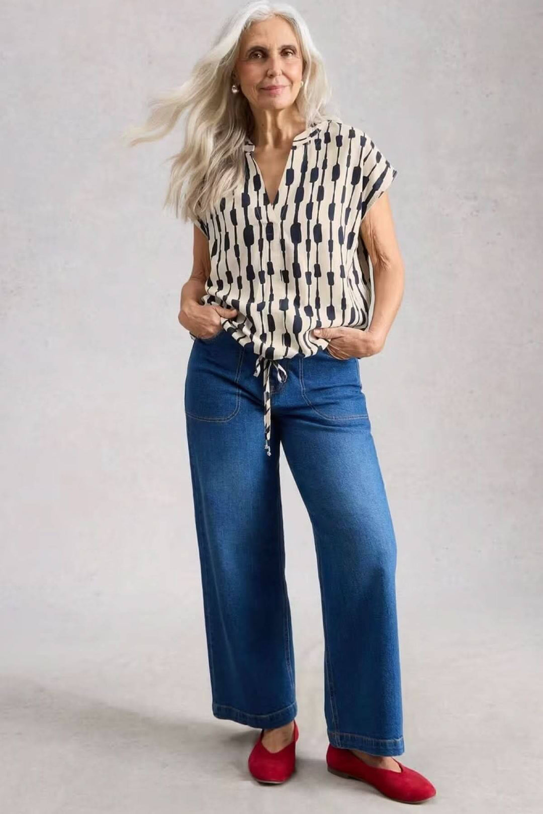 Modèle portant la Blouse Nicole en lin mélangé avec imprimé graphique, coupe fluide, encolure en V et manches courtes, style décontracté.