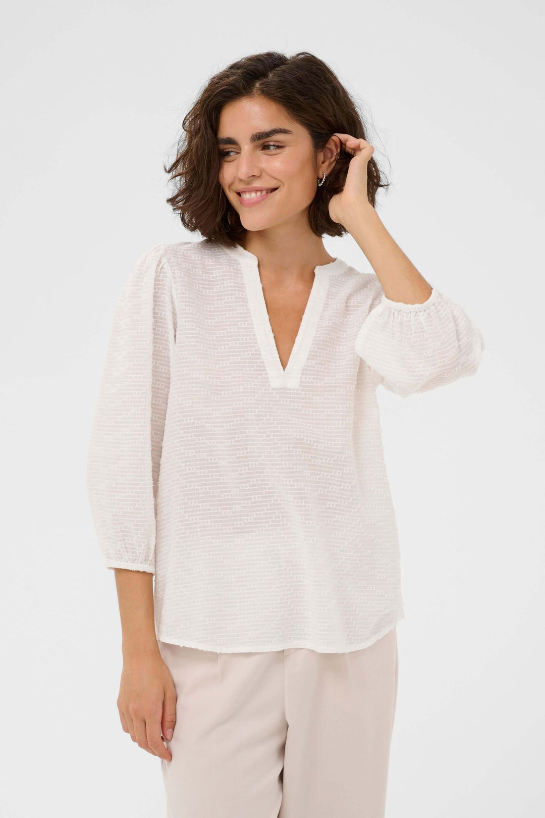 Blouse Penelope texturée à manches trois-quarts avec encolure en V, tissu léger et confortable, modèle féminin et moderne.