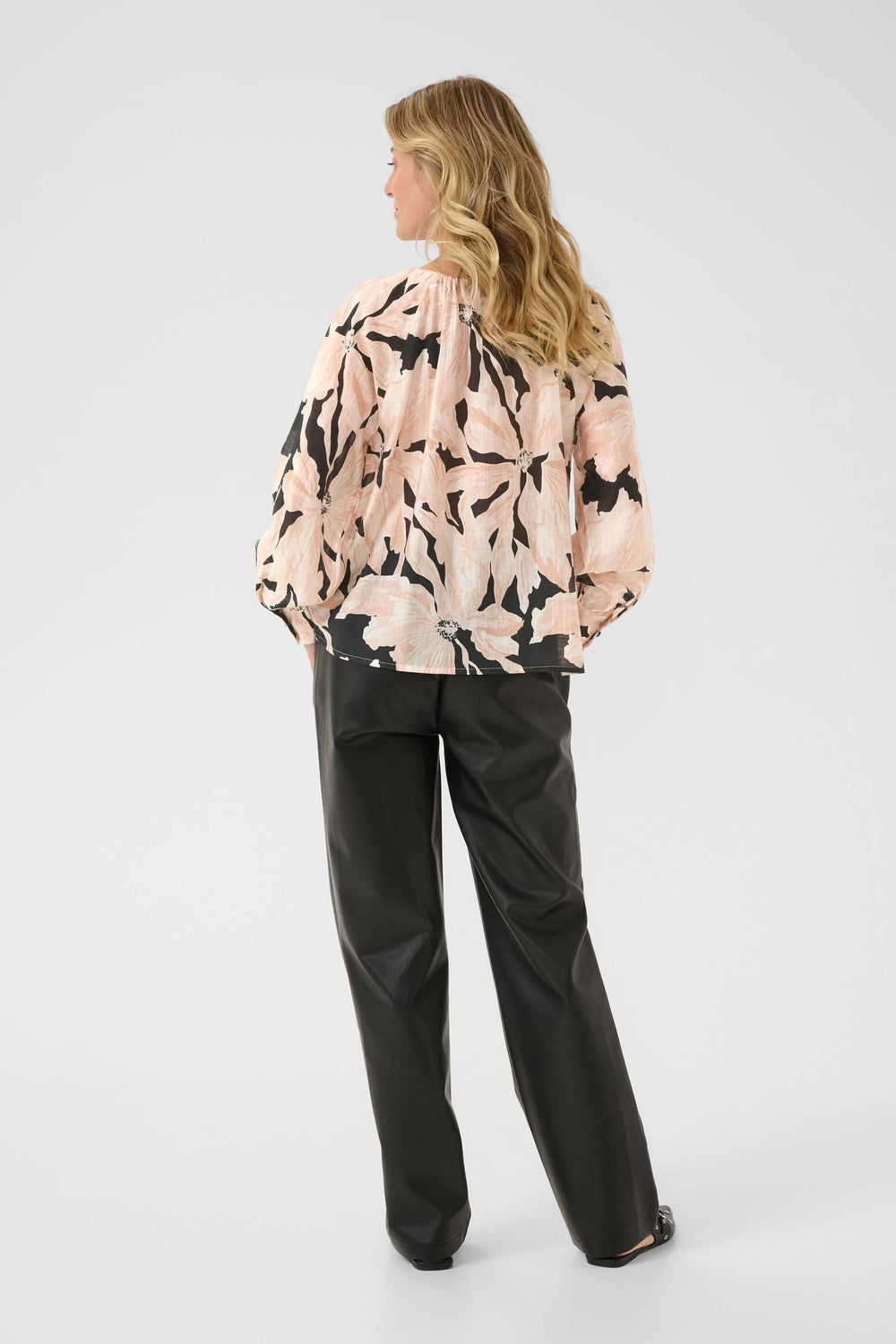 Femme portant la Blouse Reese avec imprimé artistique, manches longues bouffantes, et encolure froncée.