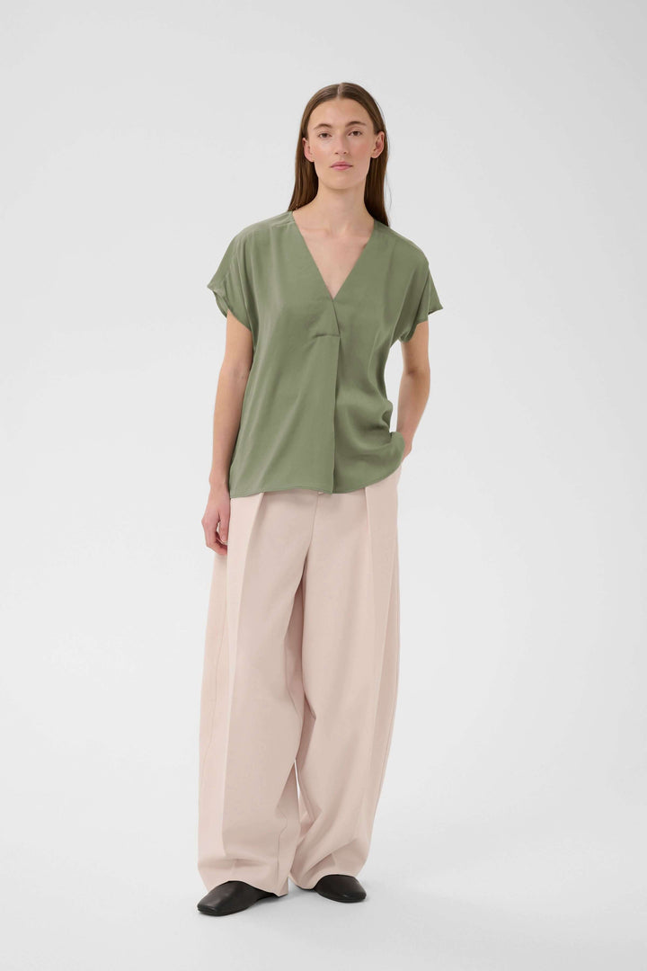 Blouse Rinda verte fluide avec encolure en V, coupe droite élégante.