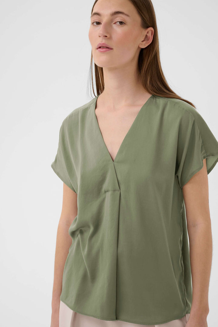 Blouse Rinda verte avec encolure en V et manches courtes, idéale pour un look féminin et raffiné au quotidien.