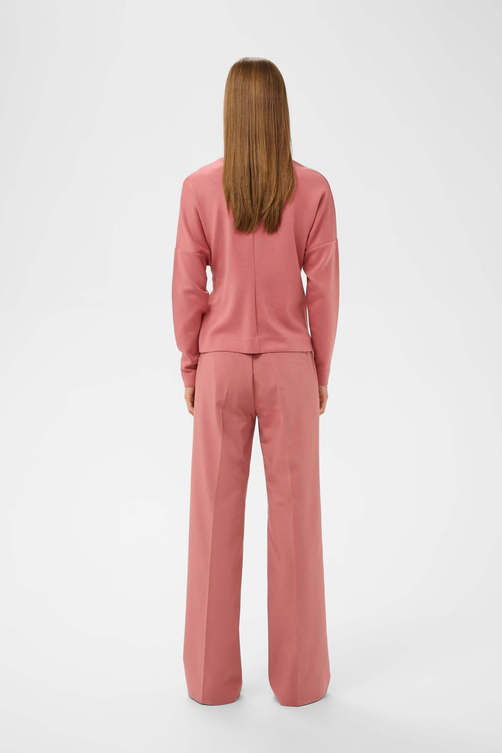 Vue arrière de la "Blouse Tricent" avec détail noué, porté avec élégance sur un ensemble coordonné rose.